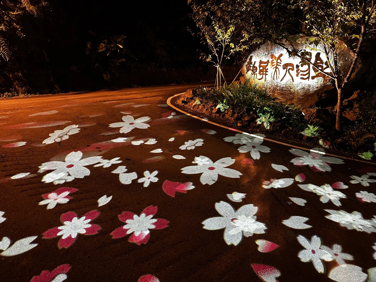 夜間迎賓入口,地面花朵光影與園區招牌石