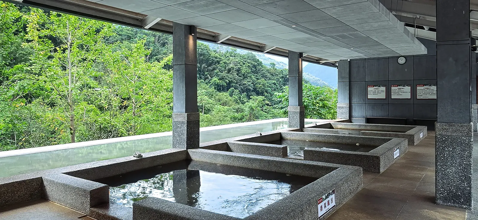 露天石砌湯池與遠山，碳酸氫鈉泉水自源頭注入